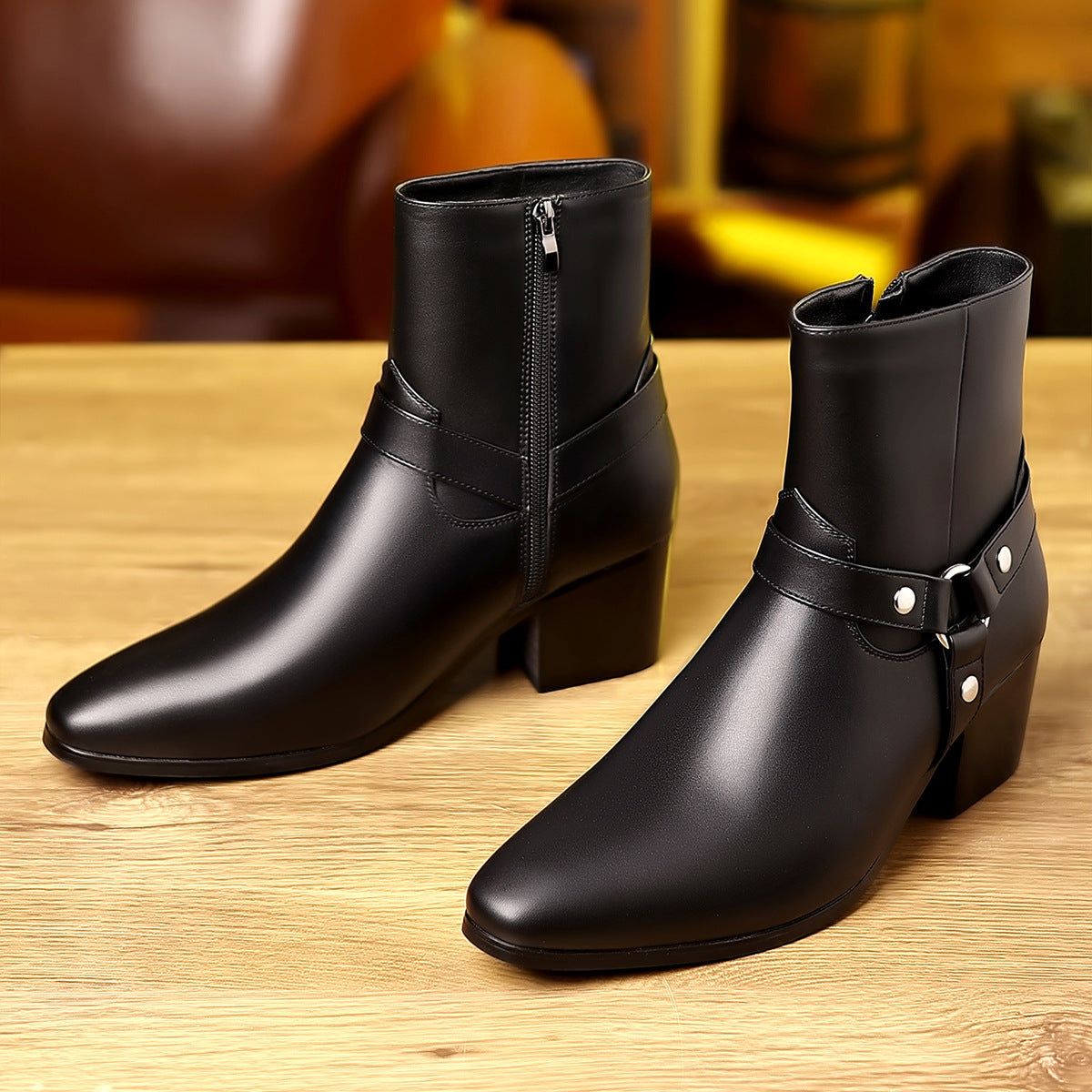 Pair of black leather boots with buckles on a wooden surface