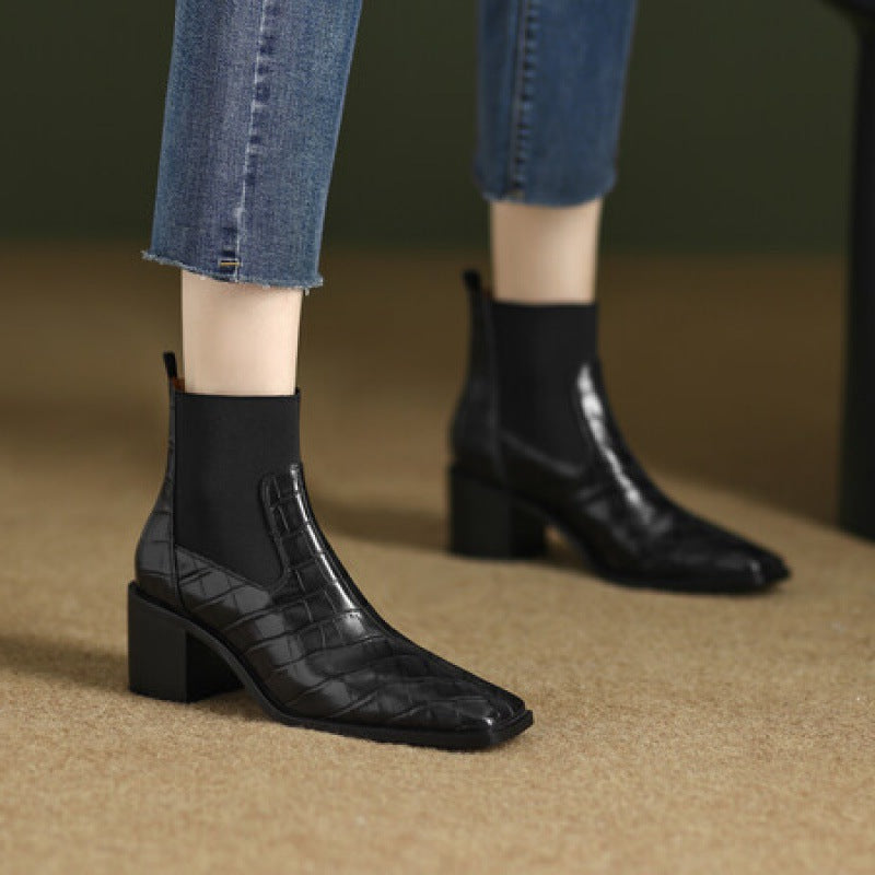 Black quilted ankle boots worn with blue jeans on a neutral background