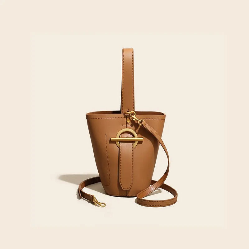 Brown leather bucket bag with gold hardware on a beige background