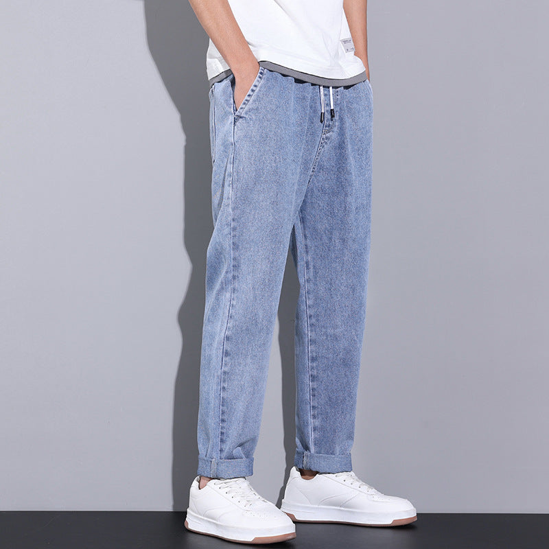 Person wearing light blue jeans and white sneakers on a gray background