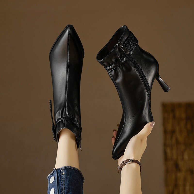 Black high-heeled boots being held against a brown background