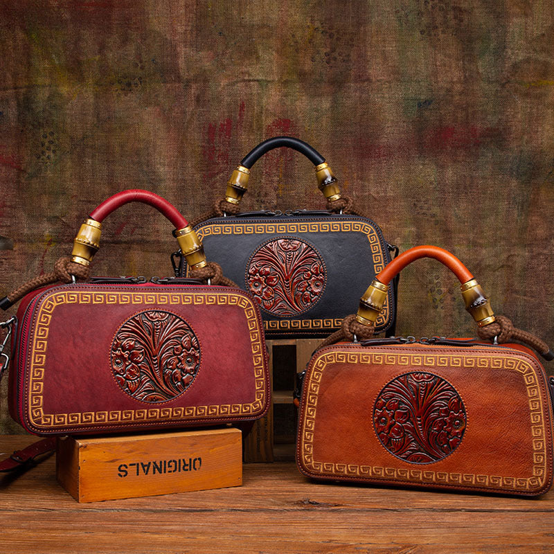 Three leather handbags with intricate designs on a wooden surface and textured brown background.