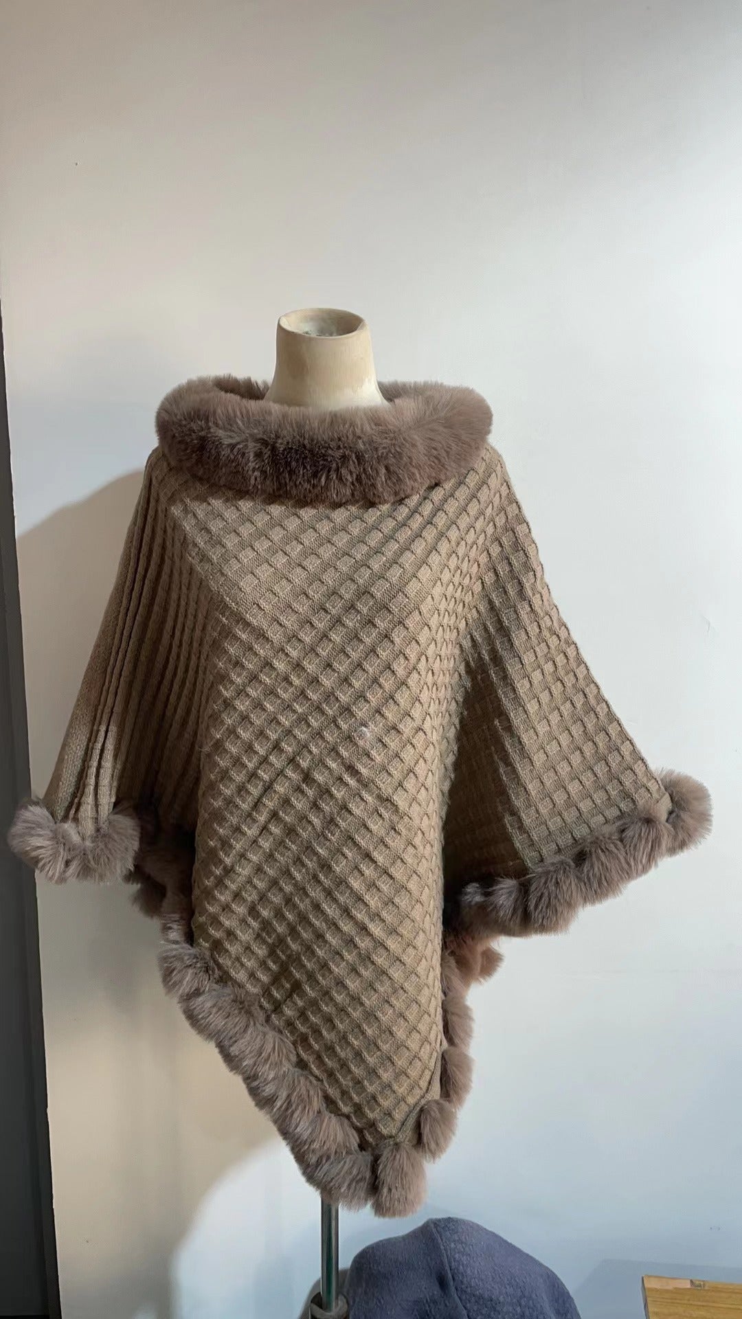 Brown textured poncho with fur trim on a mannequin against a plain background