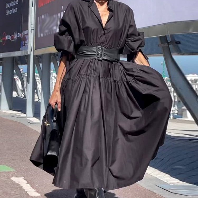 Person wearing a black dress with a belt in an urban setting