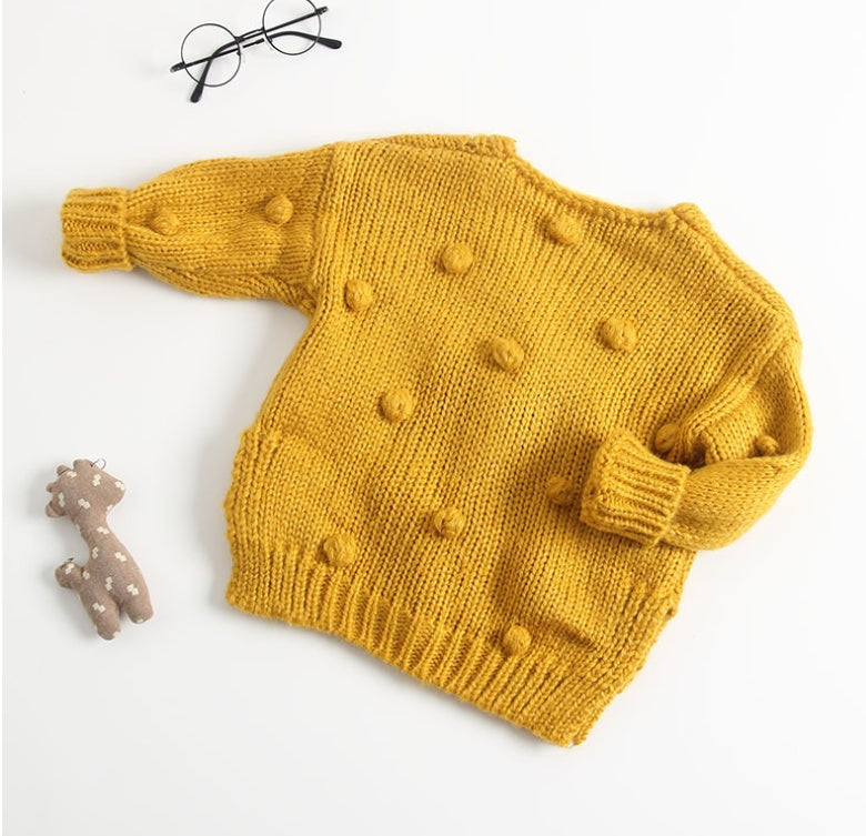 Yellow knitted sweater with bobble details on a white background