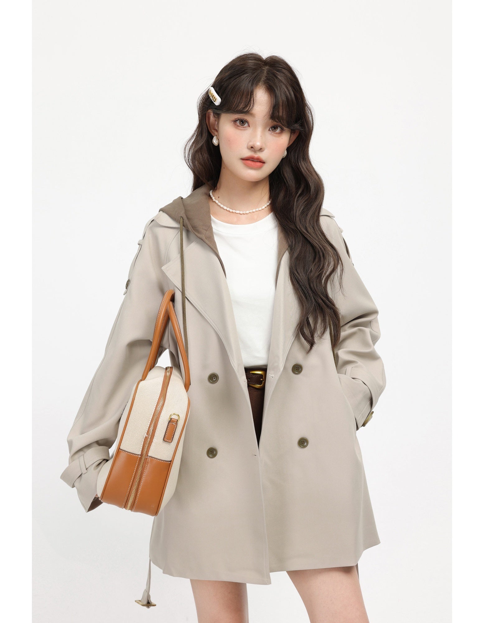 Woman wearing a beige trench coat holding a brown and white handbag on a white background by millivan