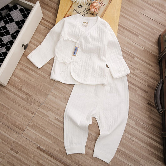 White baby outfit laid out on a wooden floor