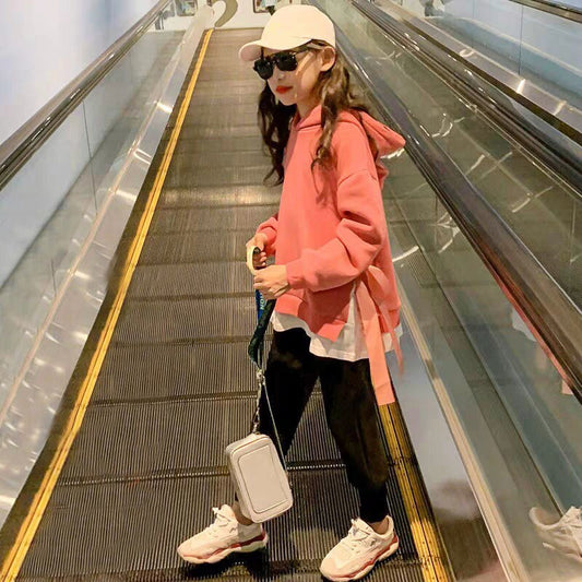 Person in a pink hoodie and black pants walking down an escalator.