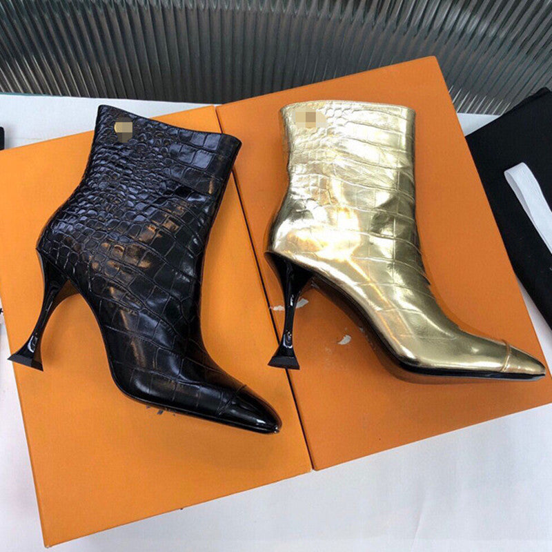 Black and gold high-heeled boots on an orange box