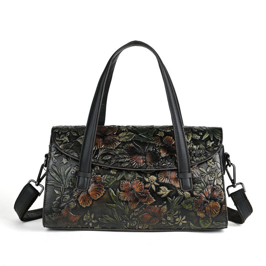 Floral embossed handbag with black handles on a white background