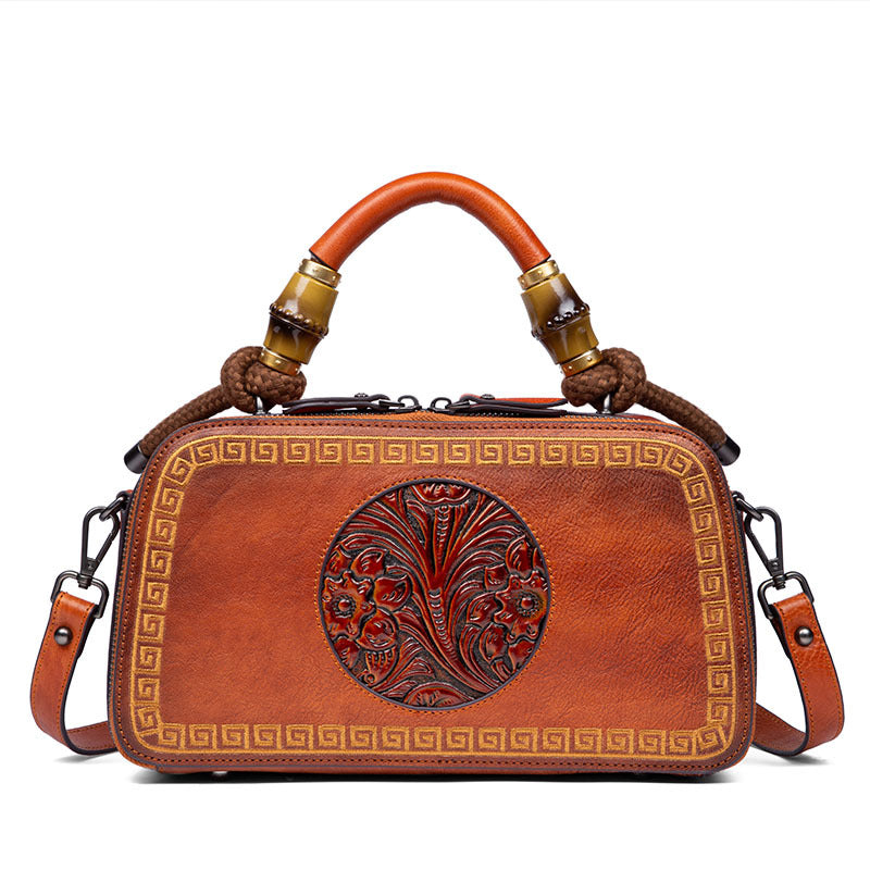 Brown leather handbag with intricate designs on a white background