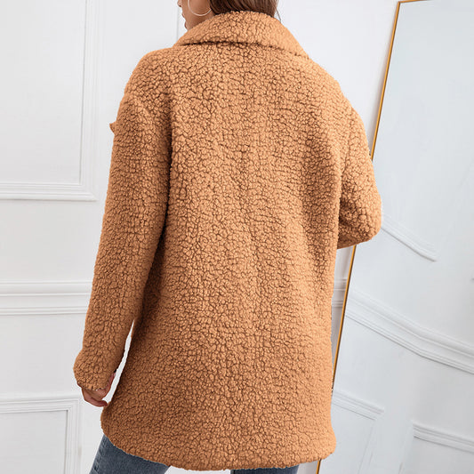 Person wearing a brown sherpa coat against a white wall.