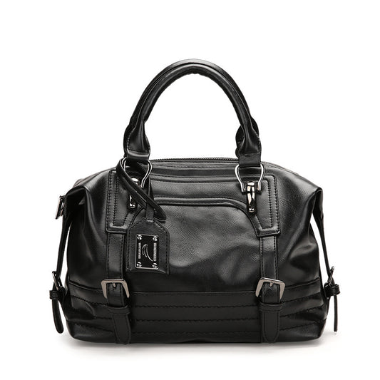 Black handbag with multiple zippers on a white background