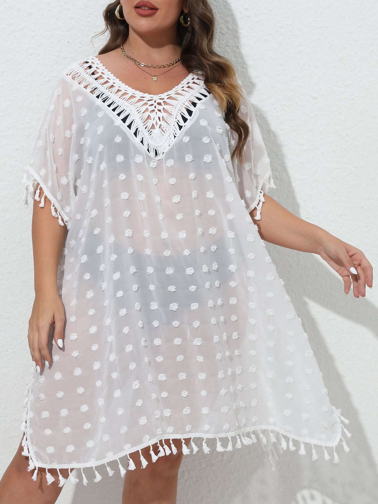 White polka dot dress with lace neckline and tassel details on a white background