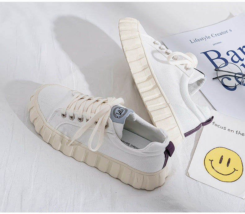 White sneakers on a white surface with a magazine in the background