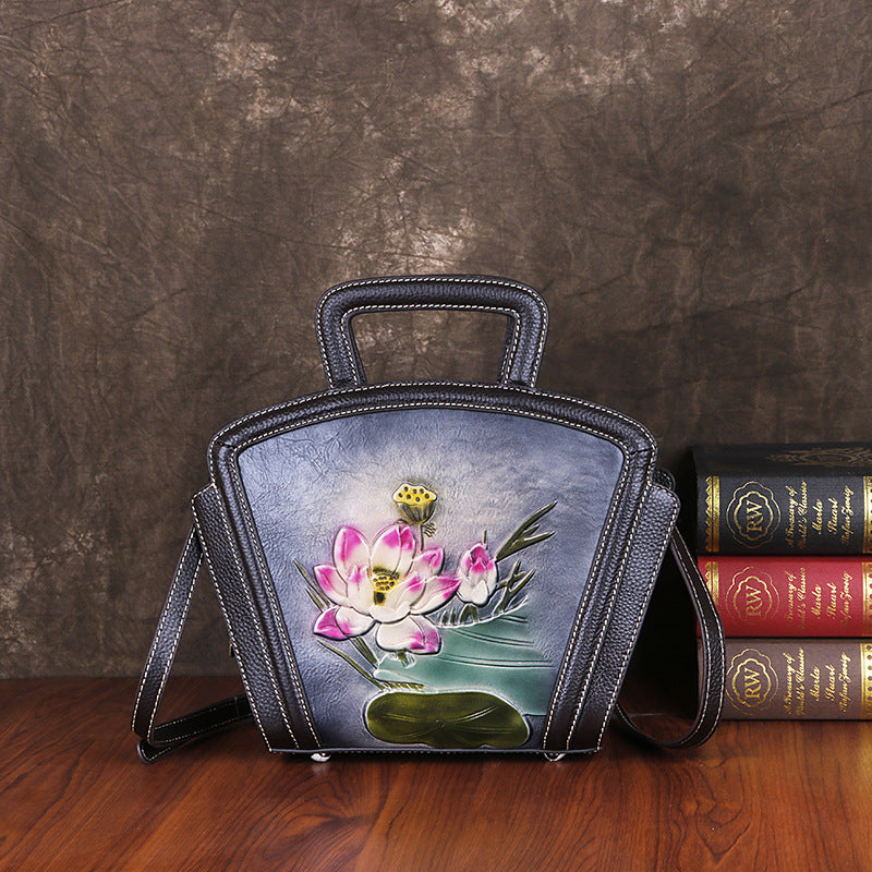 Handbag with floral design on a wooden surface with books in the background