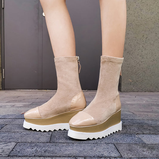 Beige platform boots worn by a person on a stone pavement.