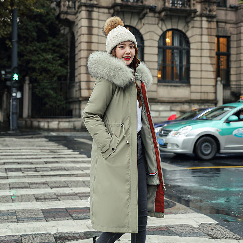 Woman in a long coat with a fur-lined hood on a city street.