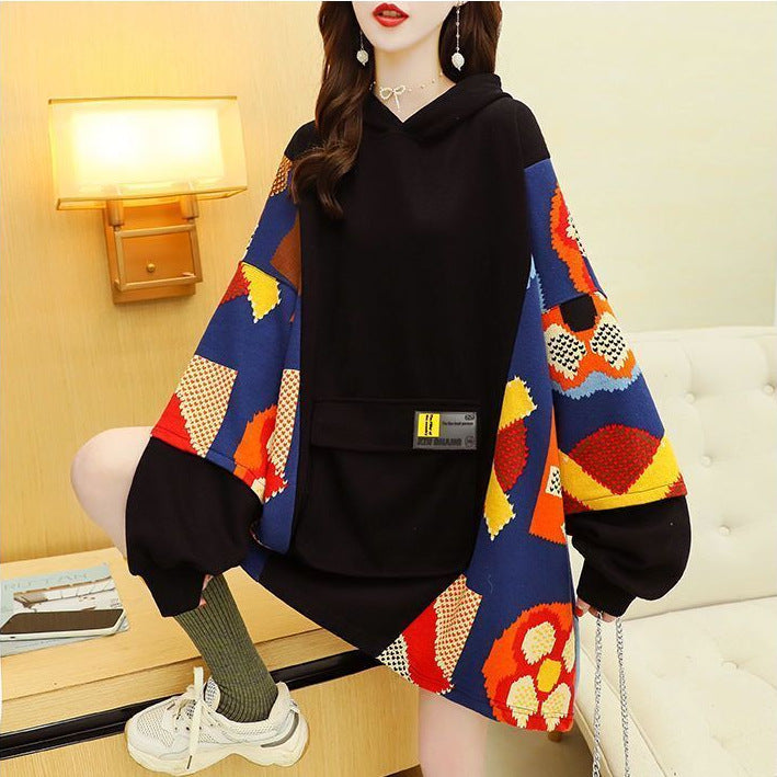 Person wearing a colorful sweater over a black outfit in a room setting.