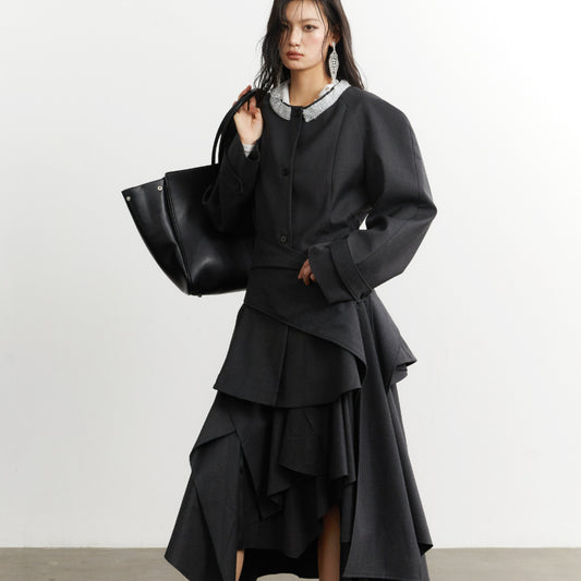 Woman wearing a black outfit with a white collar, holding a black handbag on a white background