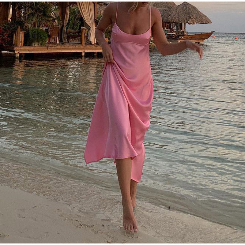 Woman in a pink dress walking on a beach with water and tropical setting in the background by millivan