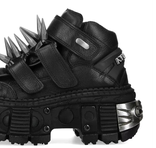 Black spiked shoes with metallic accents on a white background