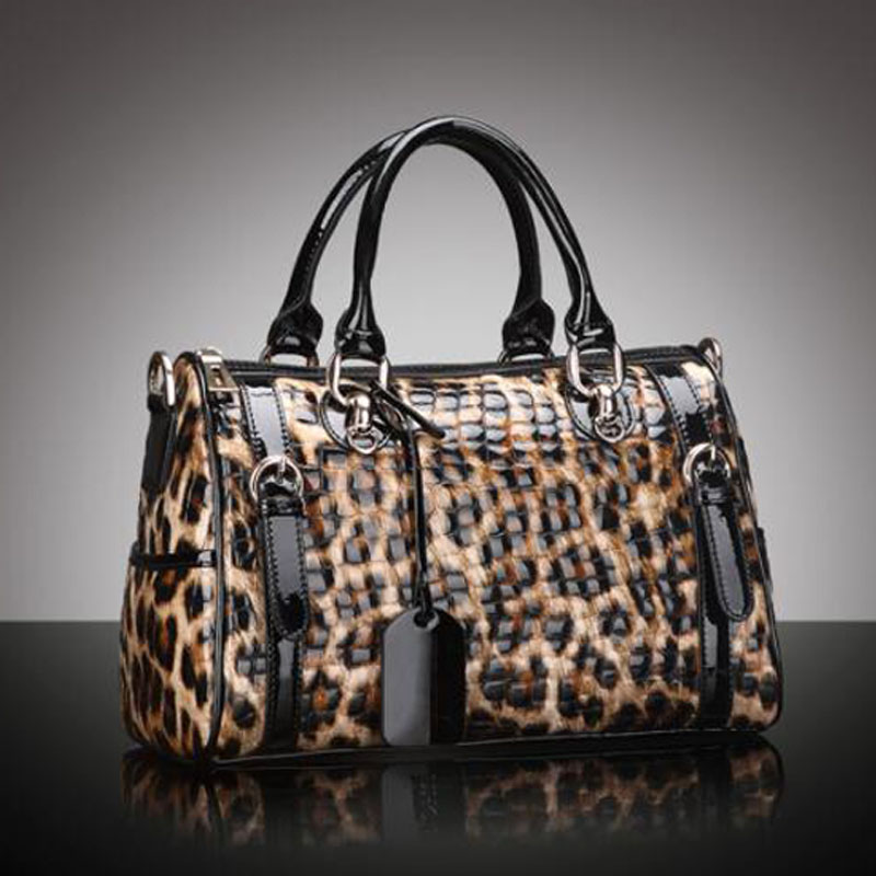 Leopard print handbag with black accents on a reflective surface and gray background