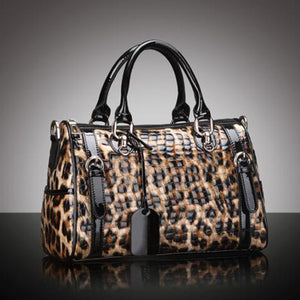 Leopard print handbag with black accents on a reflective surface and gray background