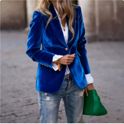 Person wearing a blue blazer, white shirt, and jeans, holding a green clutch.