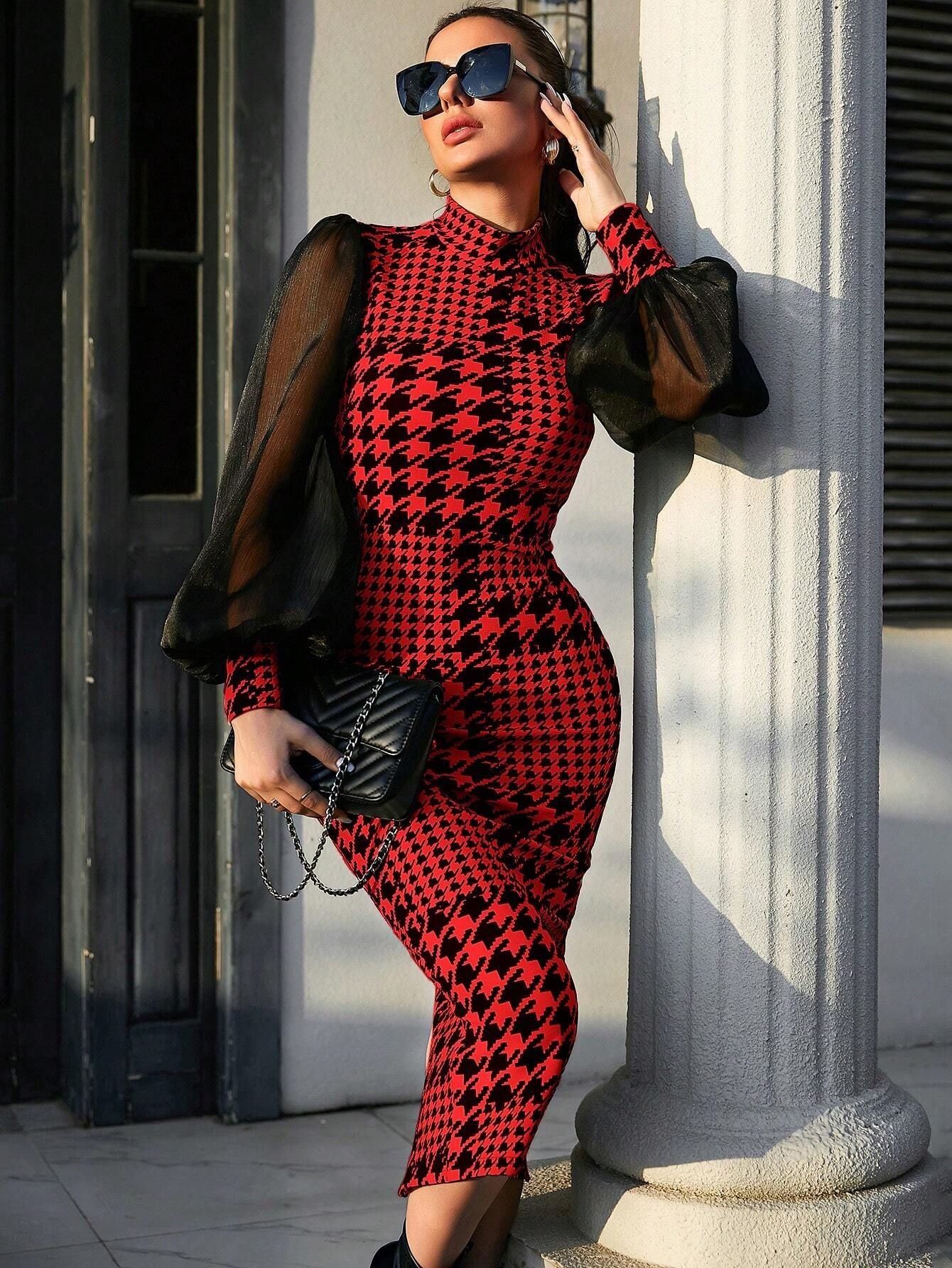 Woman in a red and black patterned outfit leaning against a column.