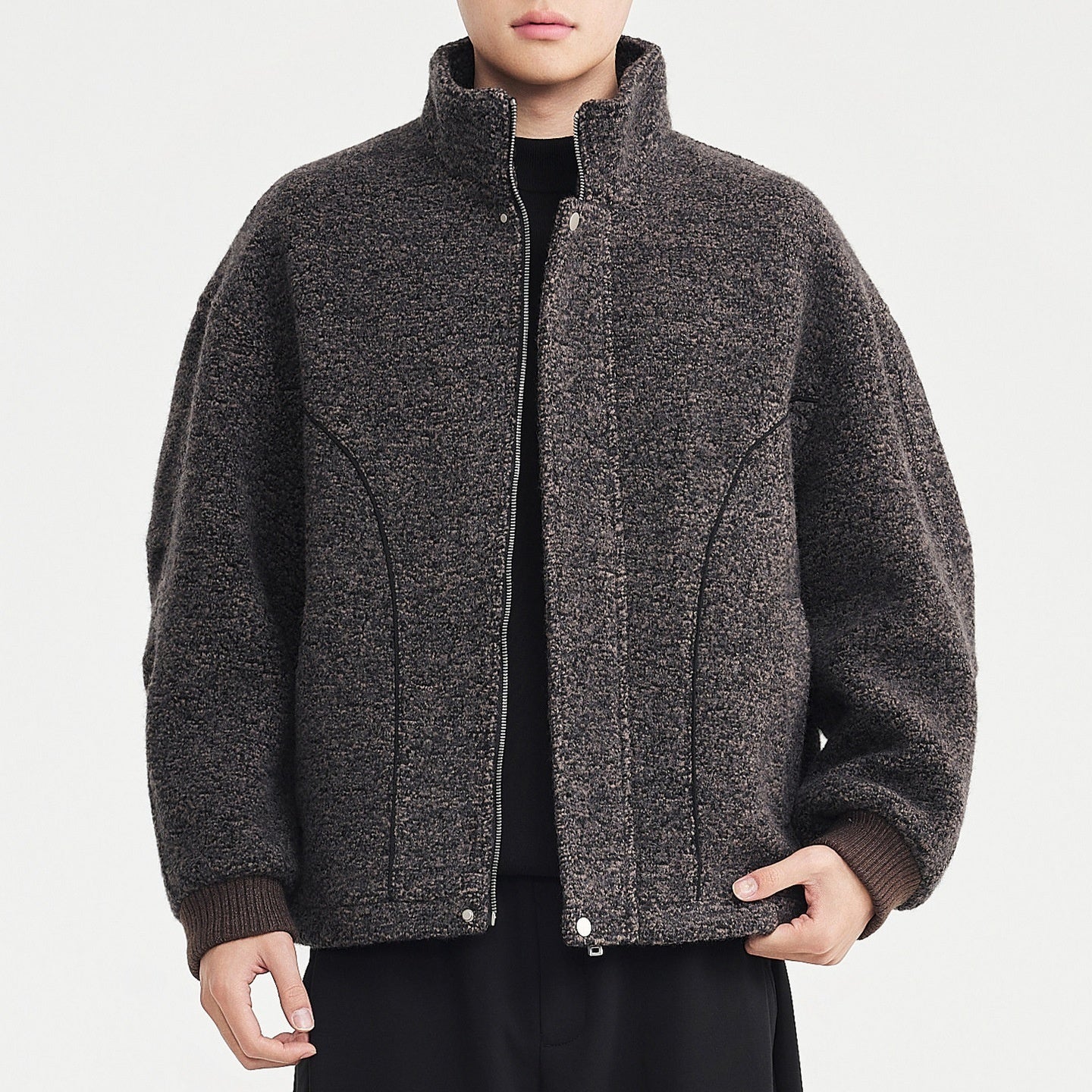 Person wearing a gray textured jacket on a light gray background
