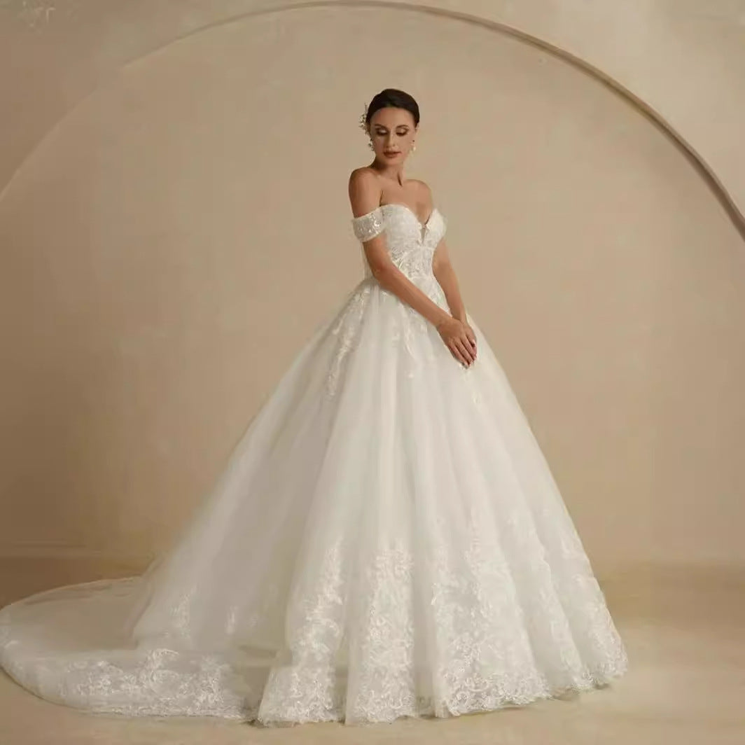 Woman wearing a white lace wedding dress against a beige background
