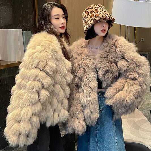 Two women wearing fluffy beige coats indoors.