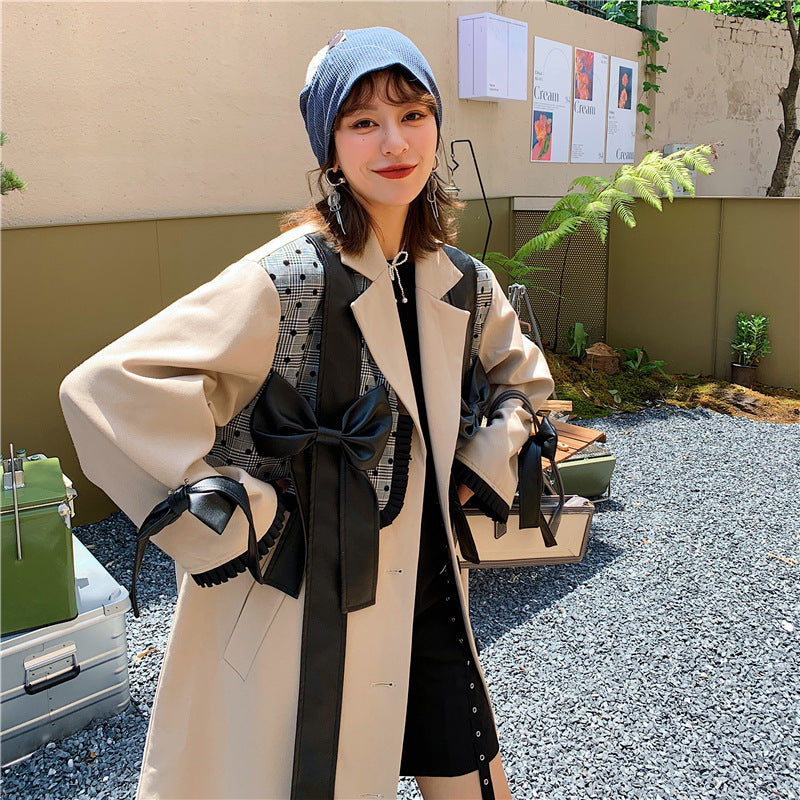 Woman wearing a beige coat with a black bow, standing outdoors. by millivan