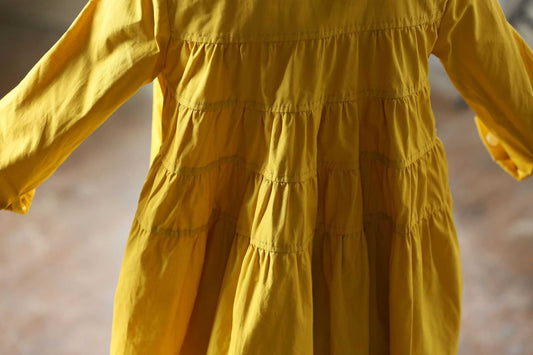 Yellow dress with long sleeves and a tiered skirt on a blurred background