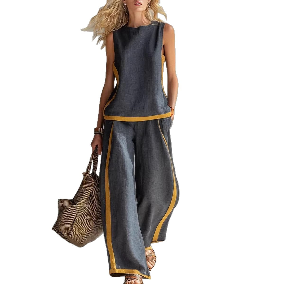 Woman wearing a gray sleeveless top and wide-leg pants with yellow trim, holding a brown bag on a white background.