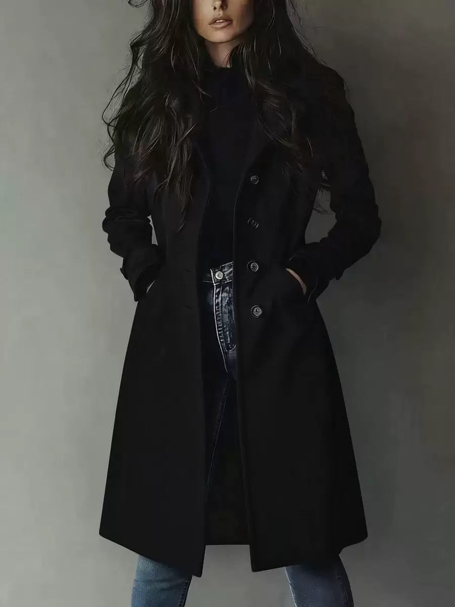 Person wearing a black coat against a plain background