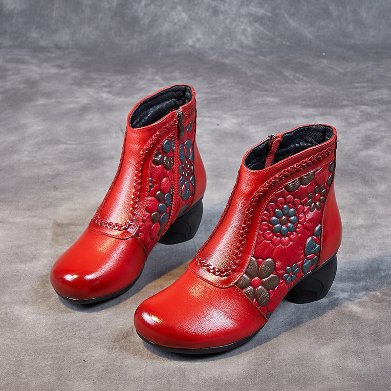 Pair of red ankle boots with floral patterns on a gray background