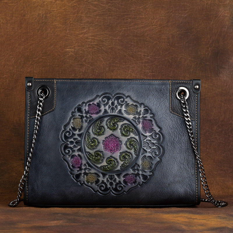 Blue leather handbag with intricate floral embroidery on a brown background