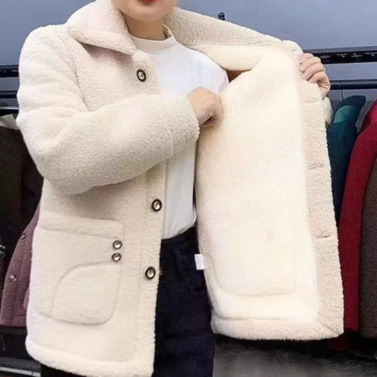 Person wearing a cream-colored fleece jacket with a plain background