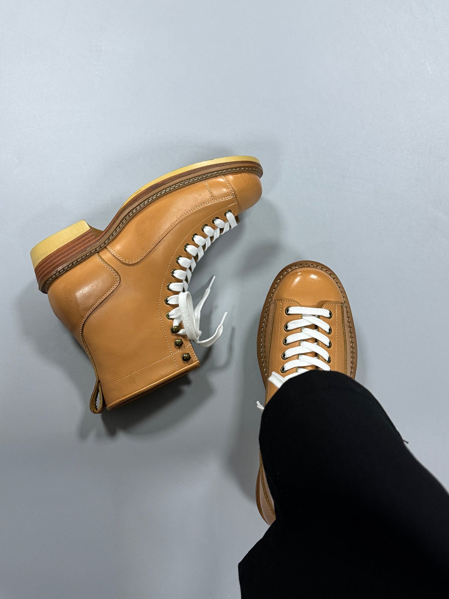 Brown leather shoes with white laces on a light gray background