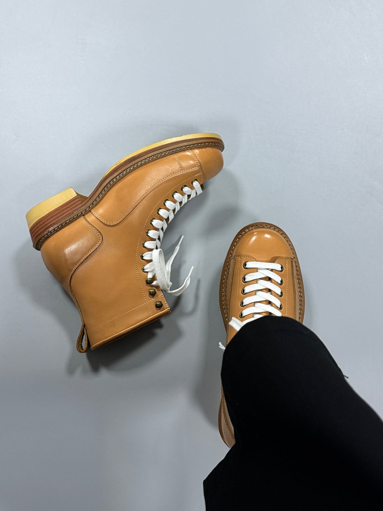 Brown leather shoes with white laces on a light gray background