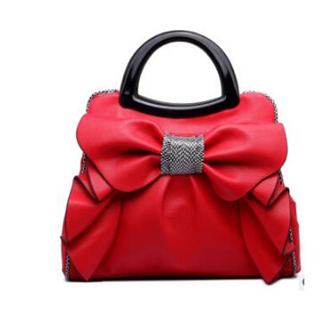 Red handbag with a large bow and black handle on a white background