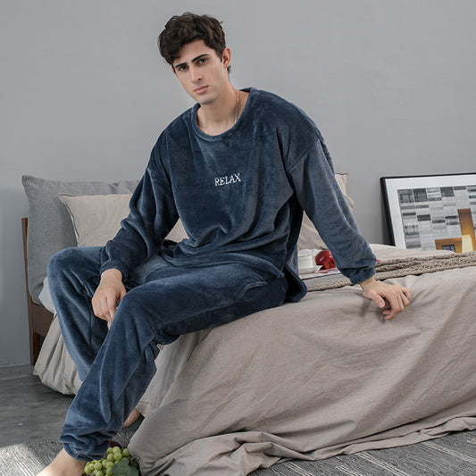 Man wearing a blue loungewear set with 'RELAX' text, sitting on a bed.