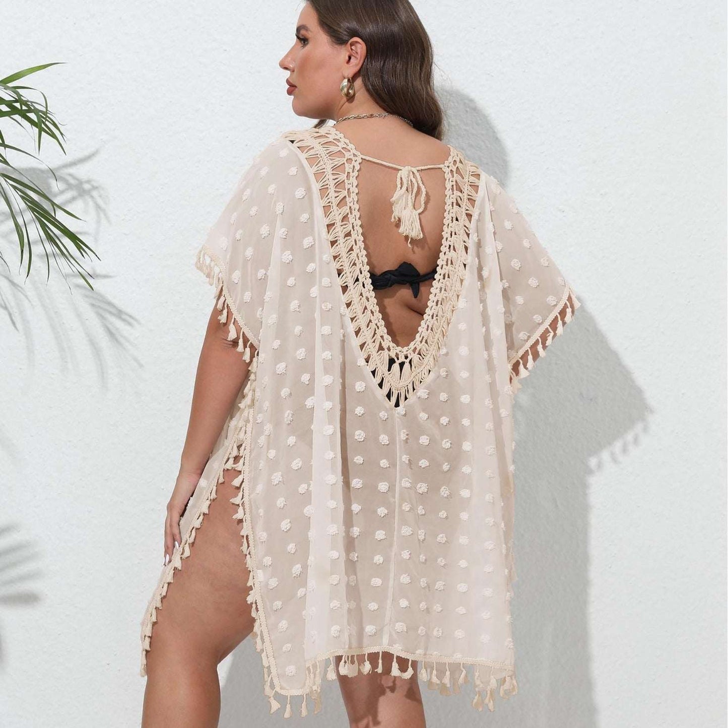 Woman wearing a beige lace cover-up against a white background