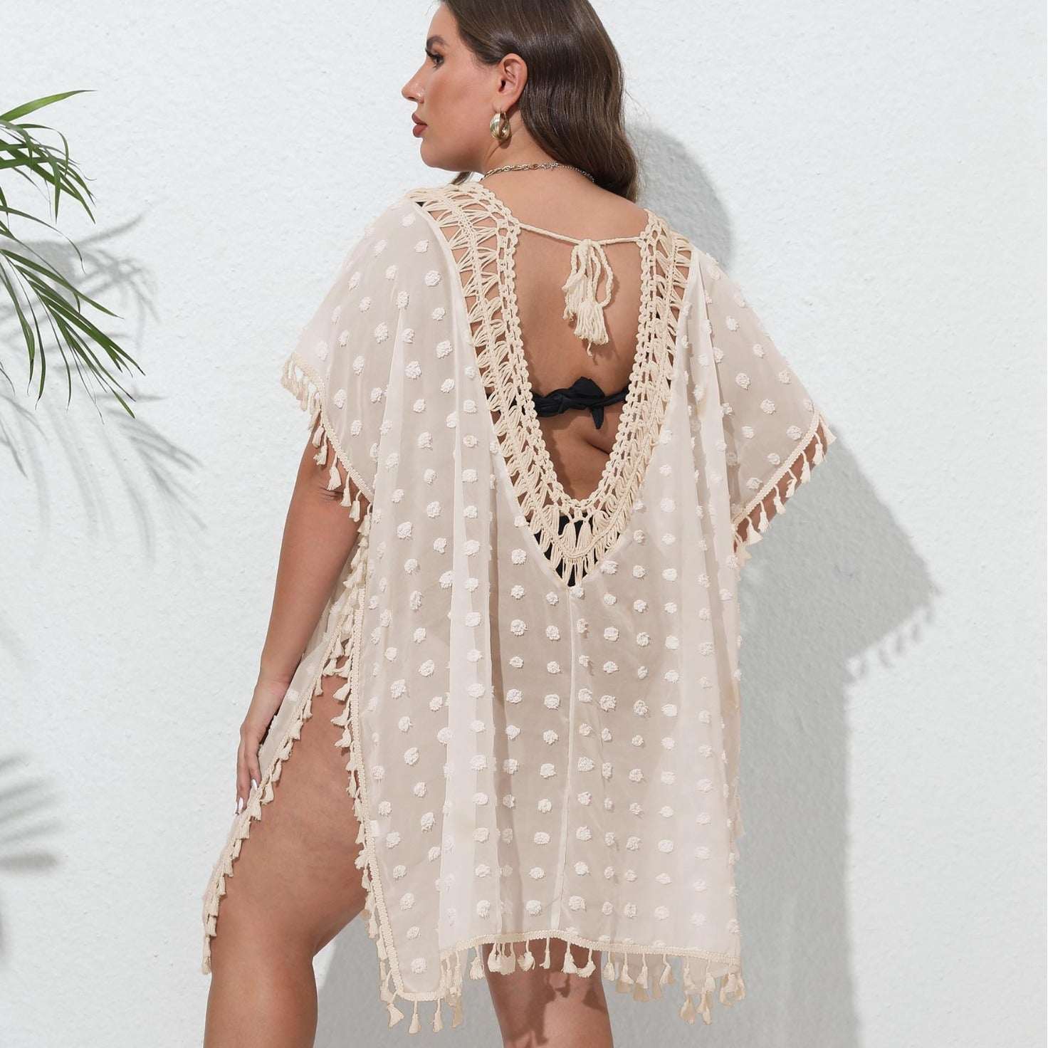 Woman wearing a beige lace cover-up against a white background