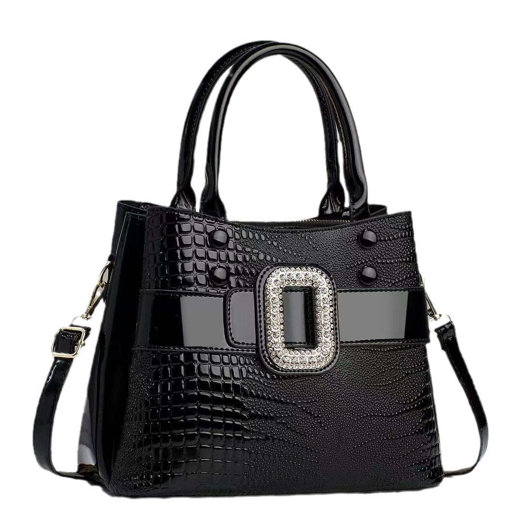 Black handbag with a decorative buckle on a white background