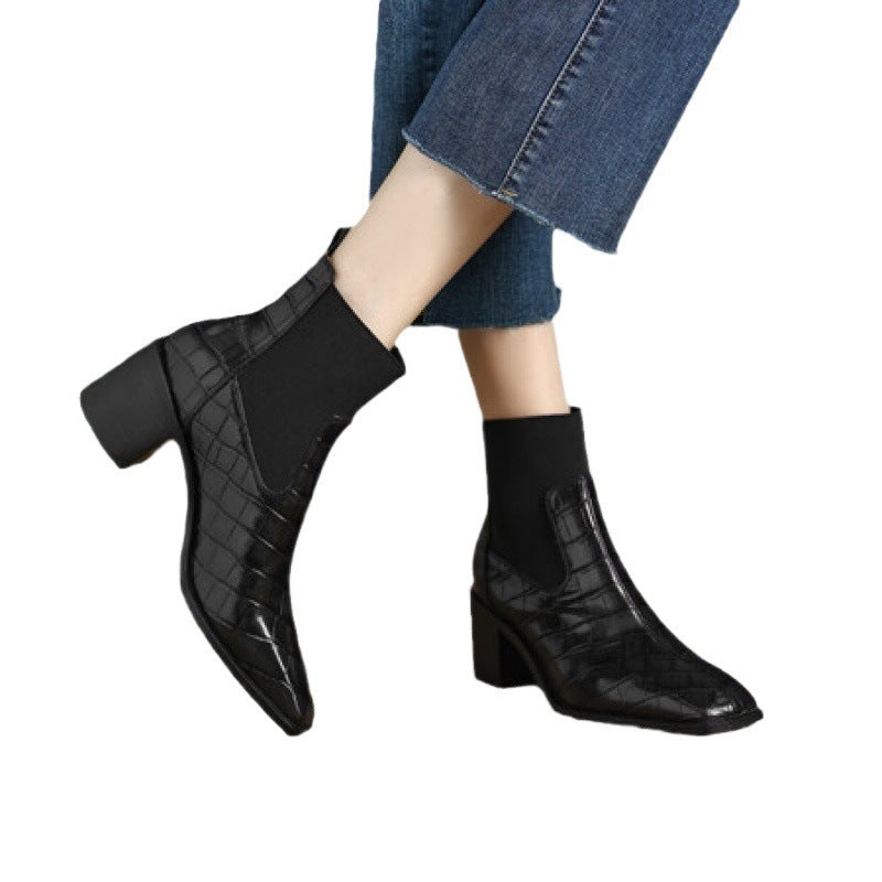Black ankle boots worn with blue jeans on a white background