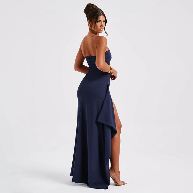 Woman wearing a strapless navy gown with a slit on a white background