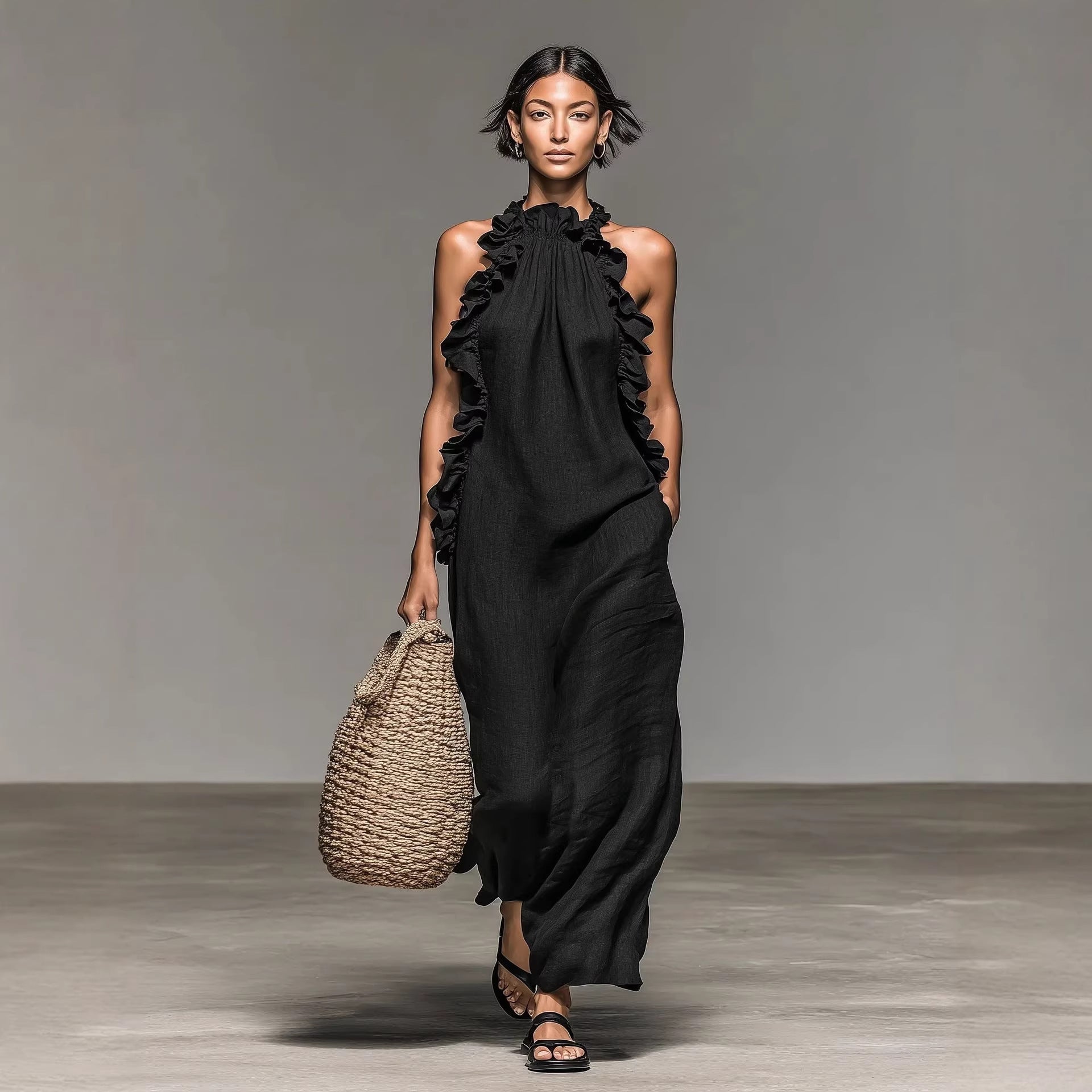 Model wearing a black dress with ruffles holding a woven bag on a plain background by millivan